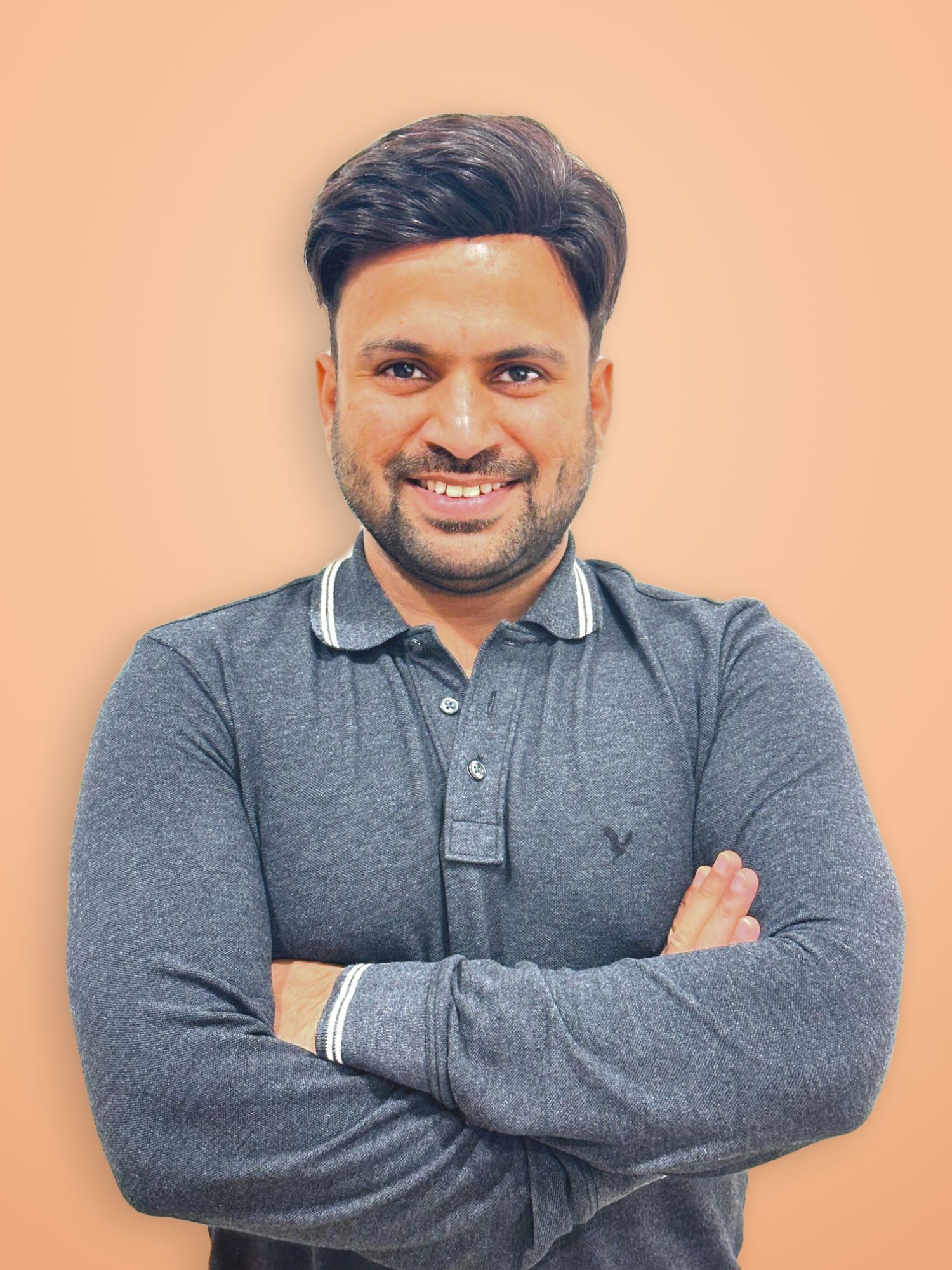 Amandeep, OneStep’s teacher, smiling with his arms folded, in a grey polo shirt